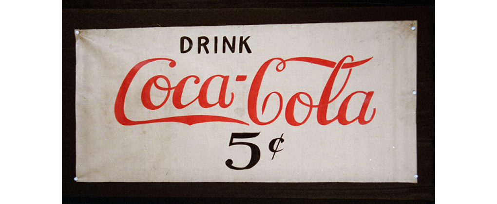 Ein altes Banner mit dem Spruch "Drink Coca-Cola"