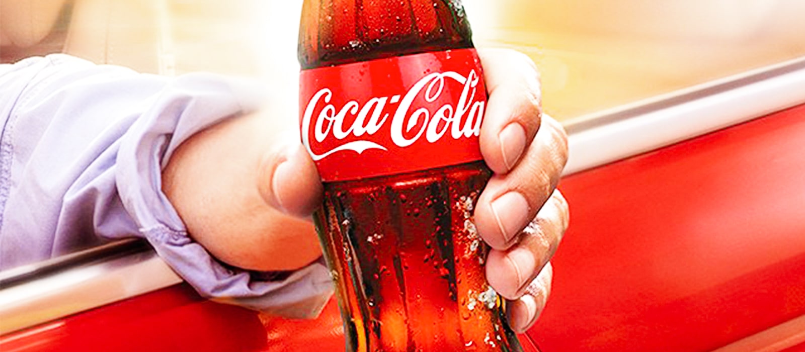 Detail of a hand holding a Coca-Cola Original bottle