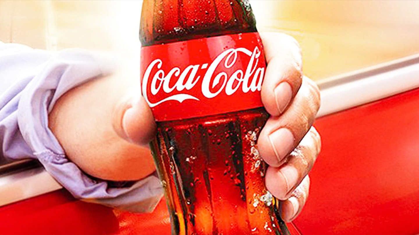 une main qui tient une bouteille Coca Cola