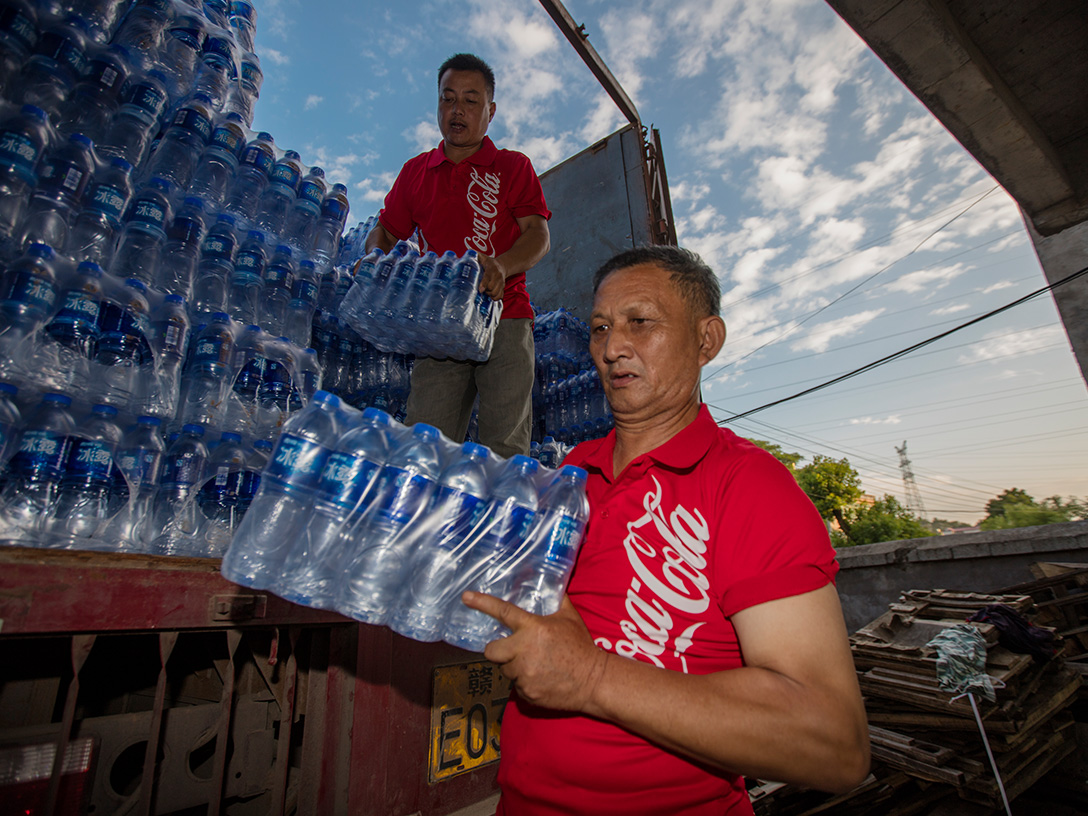 Два мушкарца истоварају пакете флаширане воде из камиона