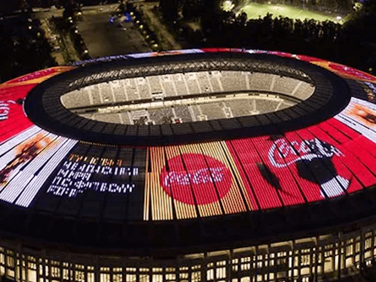 Поглед одозго на фудбалски стадион ноћу са рекламом Цоца-Цола на врху
