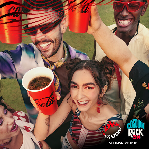 Grupo de amigos riendo levantando sus vasos de Coca-Cola en el festiva Cosquin Rock.