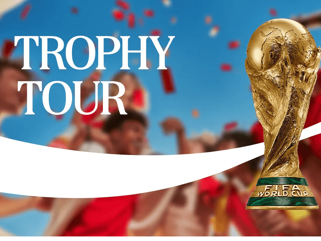 Coca-Cola Trophy Tour de la Copa Mundial de la FIFA 26™, con el trofeo dorado en primer plano sobre fondo de hinchas celebrando vestidos de rojo y azul.