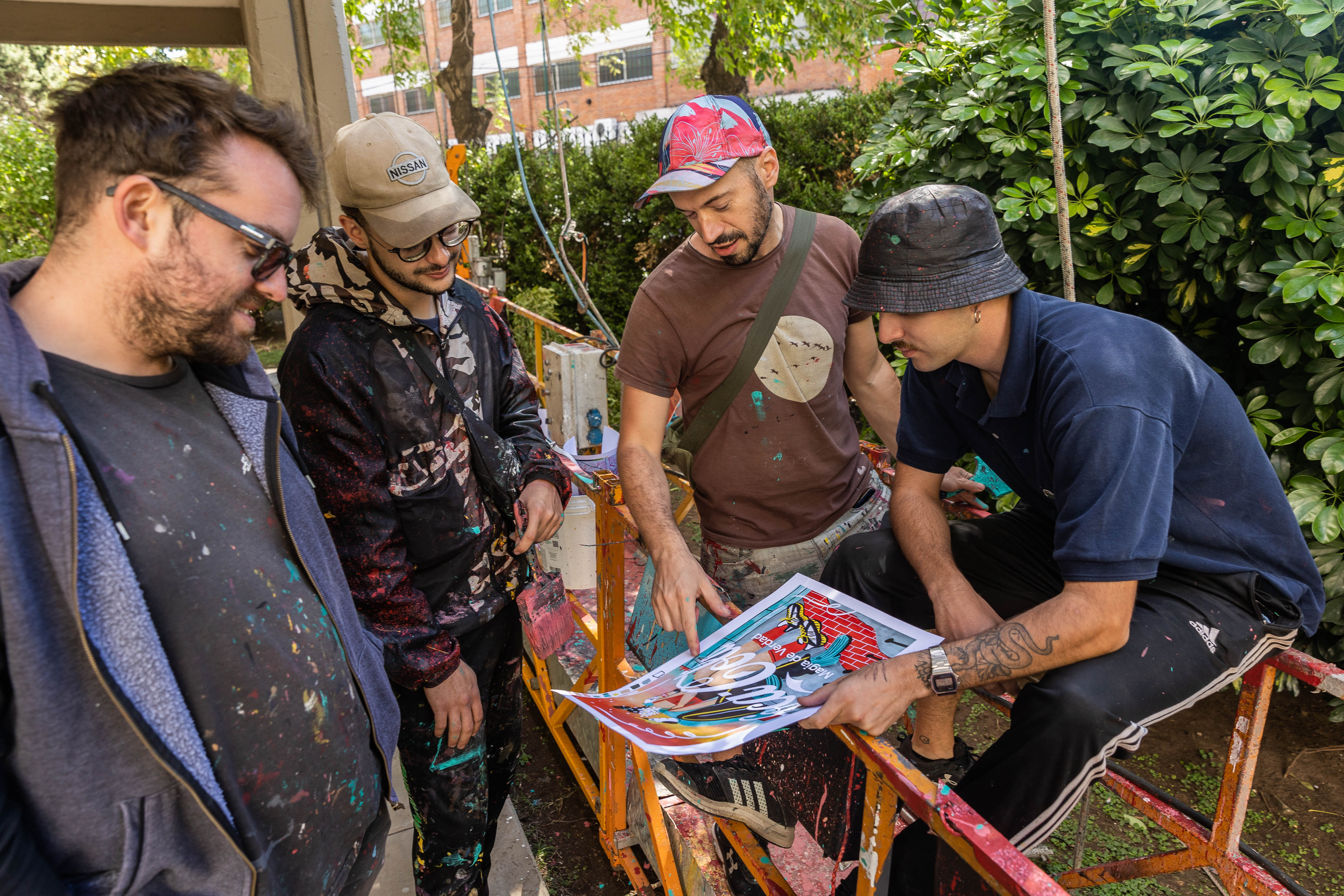 Cuatro hombres manchados de pintura mirando un dibujo