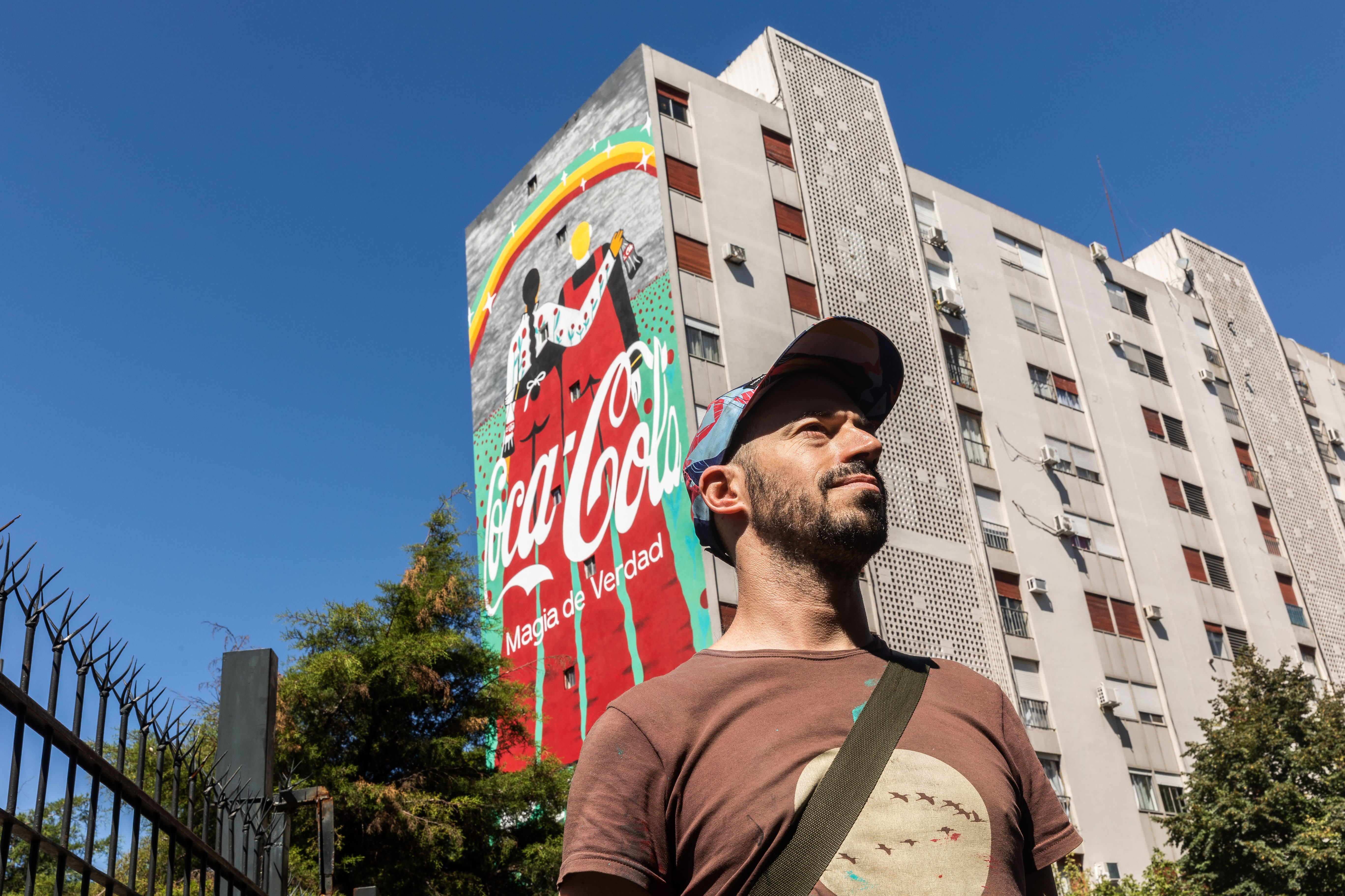 Hombre con edificio con mural de Coca-Cola de fondo
