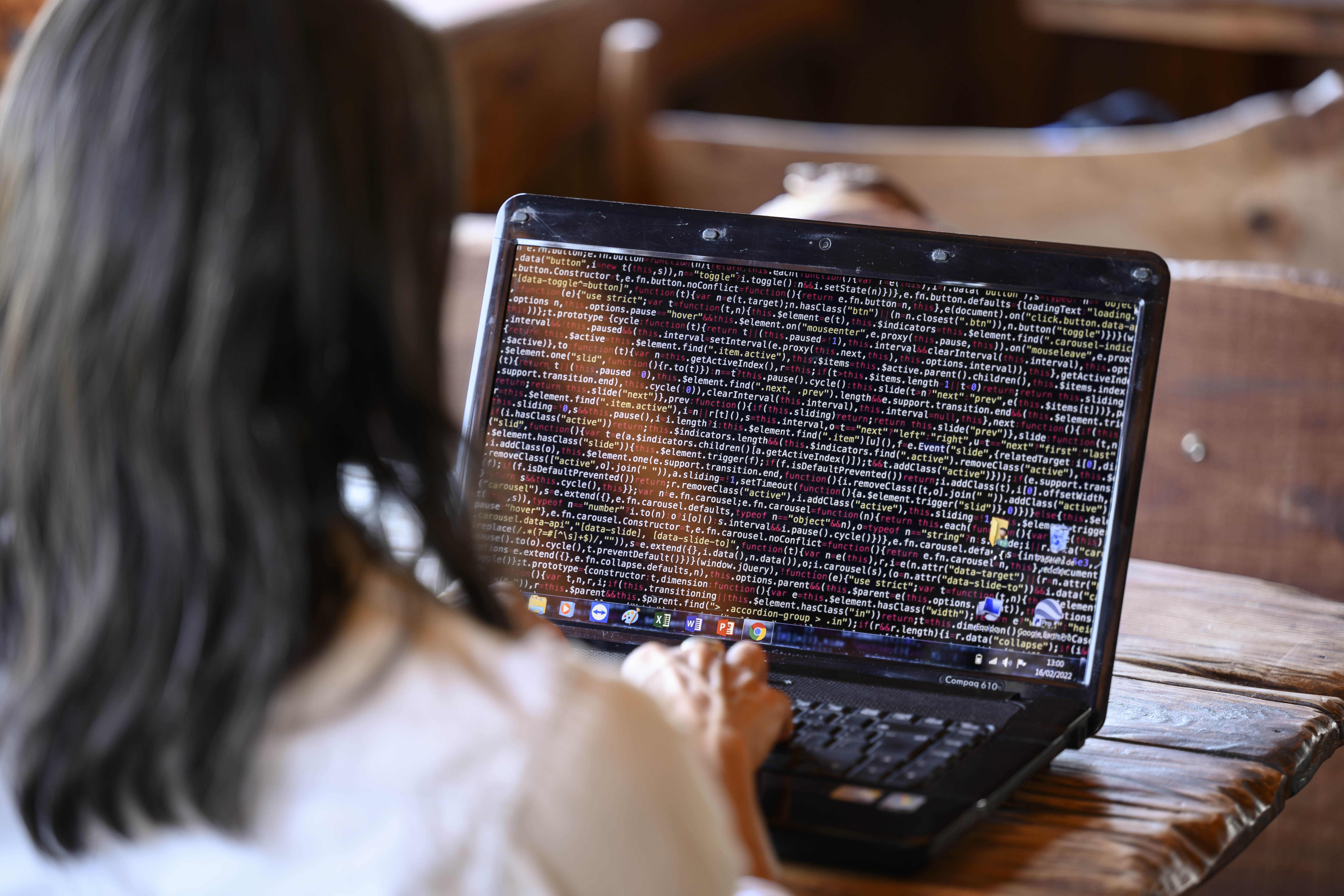 Una persona de espaldas escribiendo lenguaje de programación en ordenador portátil