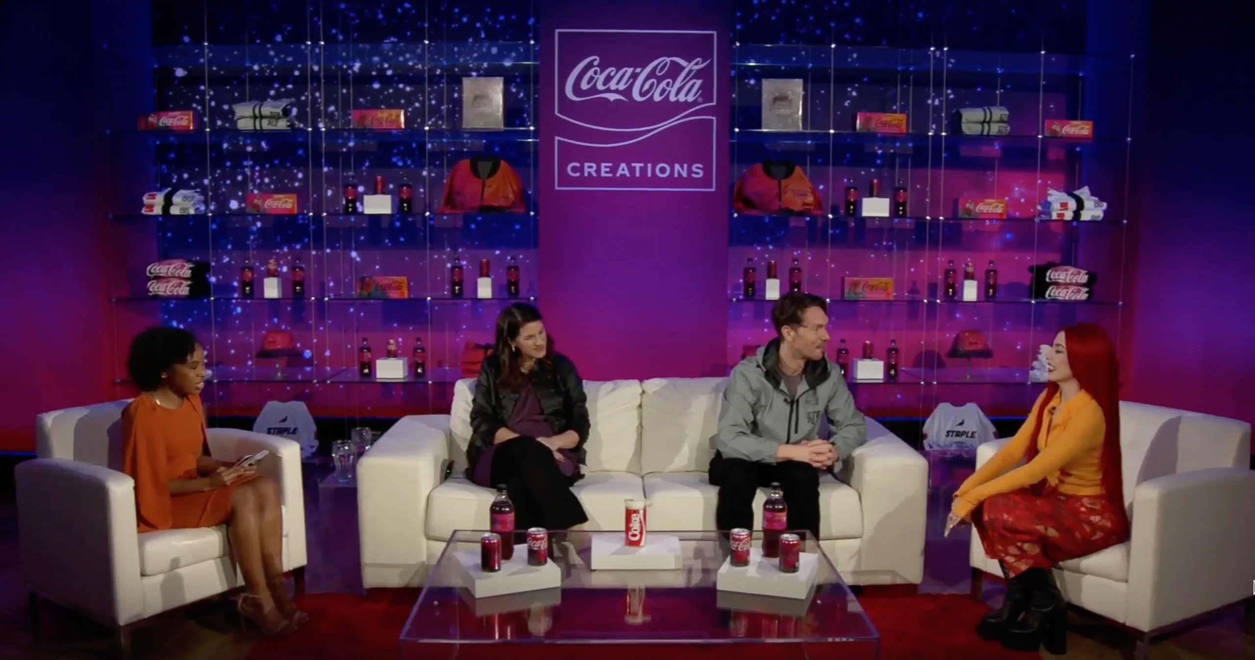 Cuatro personas conversando en sillones en un evento de Coca-Cola 