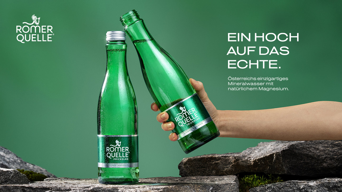 Zwei grüne Römerquelle-Prickelnd-Glasflaschen vor grünem Hintergrund, eine davon von einer Hand gehalten. Text im Bild: „Ein Hoch auf das Echte. Österreichs einzigartiges Mineralwasser mit natürlichem Magnesium."