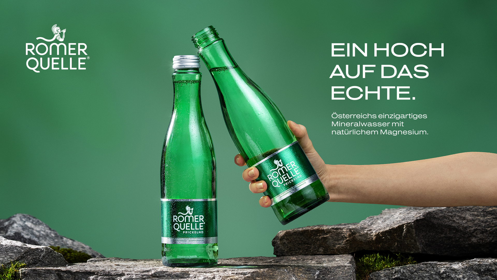 Zwei grüne Römerquelle Glasflaschen auf Natursteinen vor grünem Hintergrund – eine stehend, eine von einer Hand gereicht. Rechts der Claim: „Ein Hoch auf das Echte." Darunter: „Österreichs einzigartiges Mineralwasser mit natürlichem Magnesium."