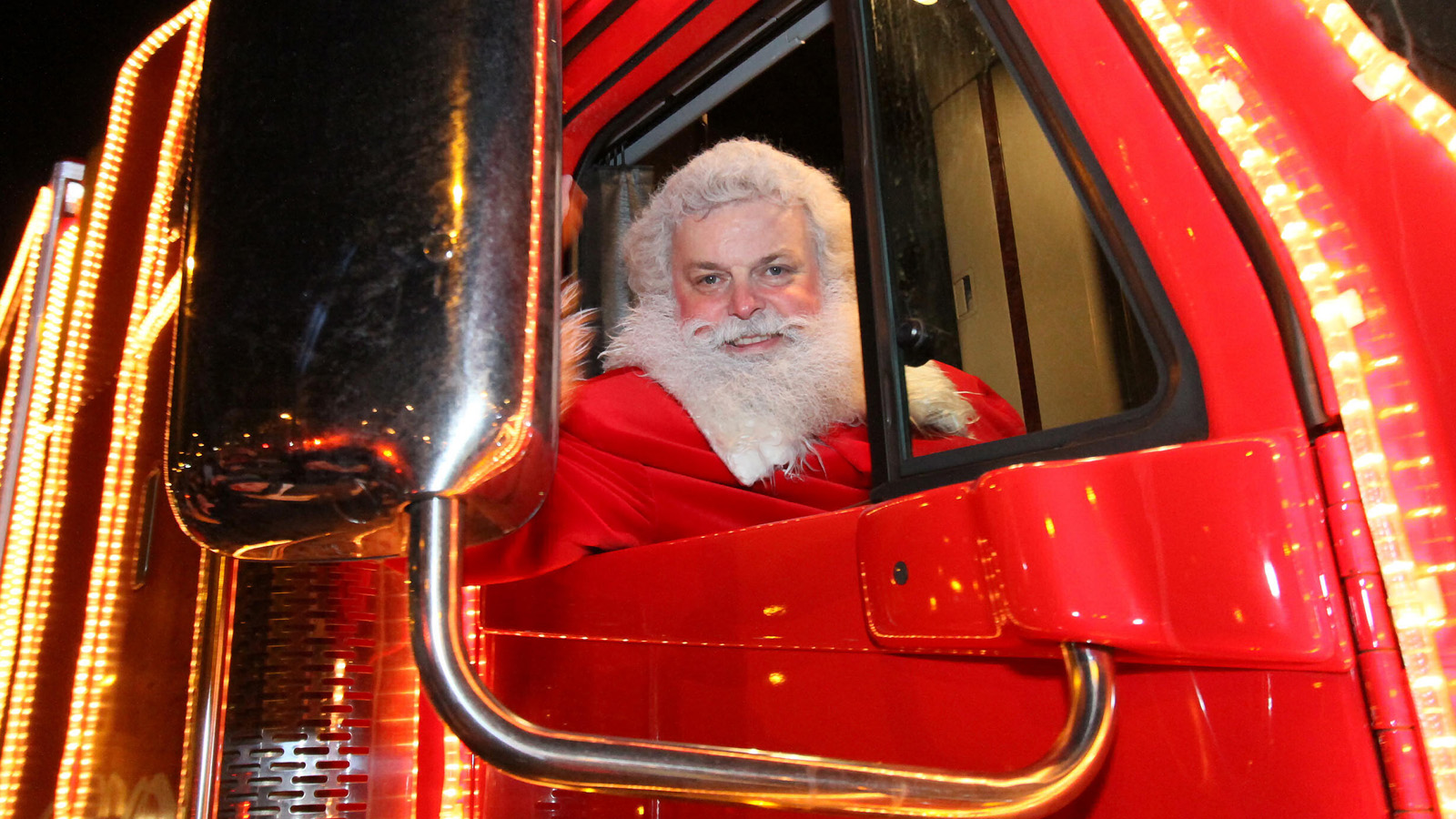 er Coca-Cola Weihnachtsmann winkt aus dem Beifahrerfenster des Coca-Cola Weihnachtstrucks