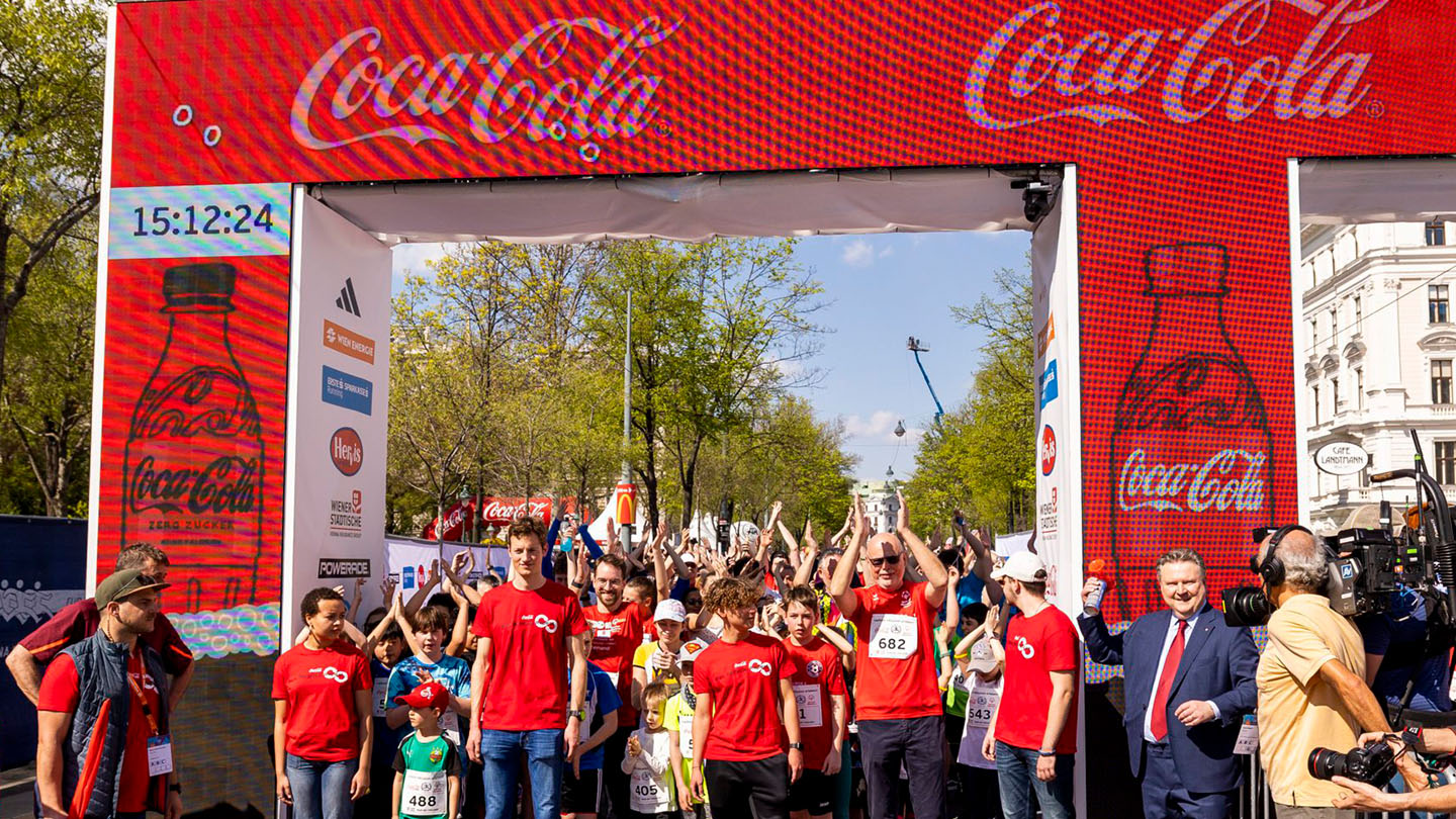 Foto von Teilnehmern des Coca-Cola Inclusion Run in Wien, darübergelegt der Text "Coca-Cola Inclusion Run - Emotionaler Auftakt des Vienna City Marathon"