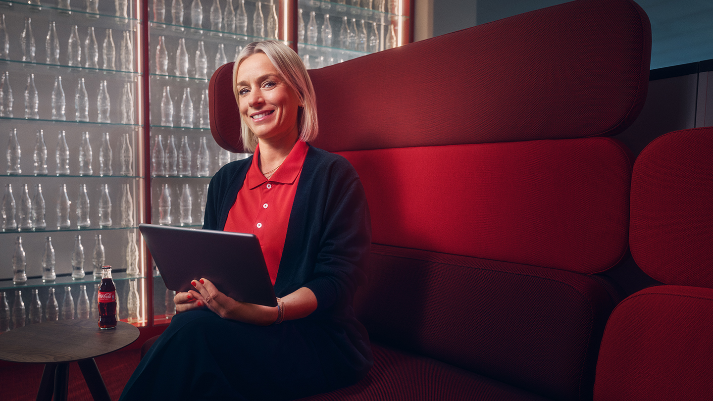 Verena Stemmer auf rotem Sofa vor Coca-Cola-Flaschenwand