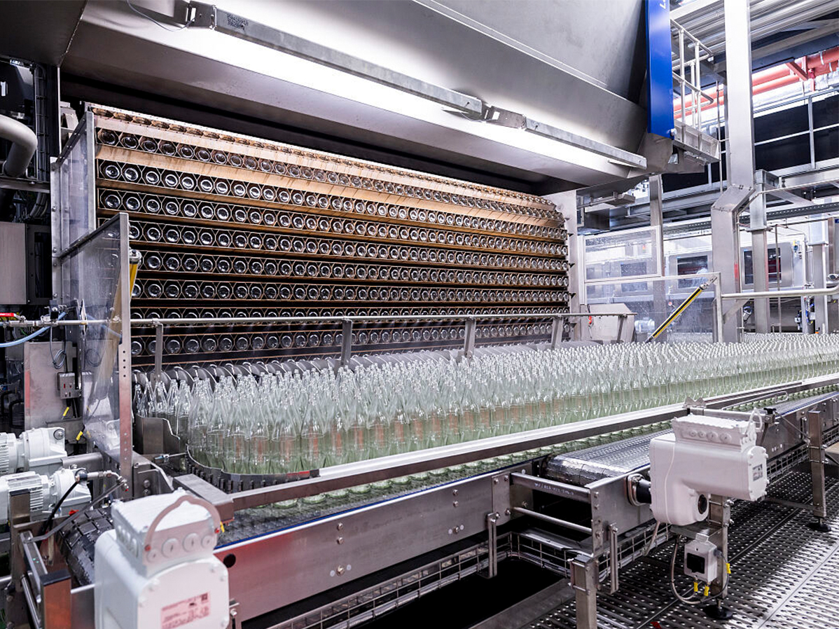 Viele Glasflachen auf einer modernen wassersparenden Waschanlage für Mehrwegflaschen in einem Produktionsgebäude