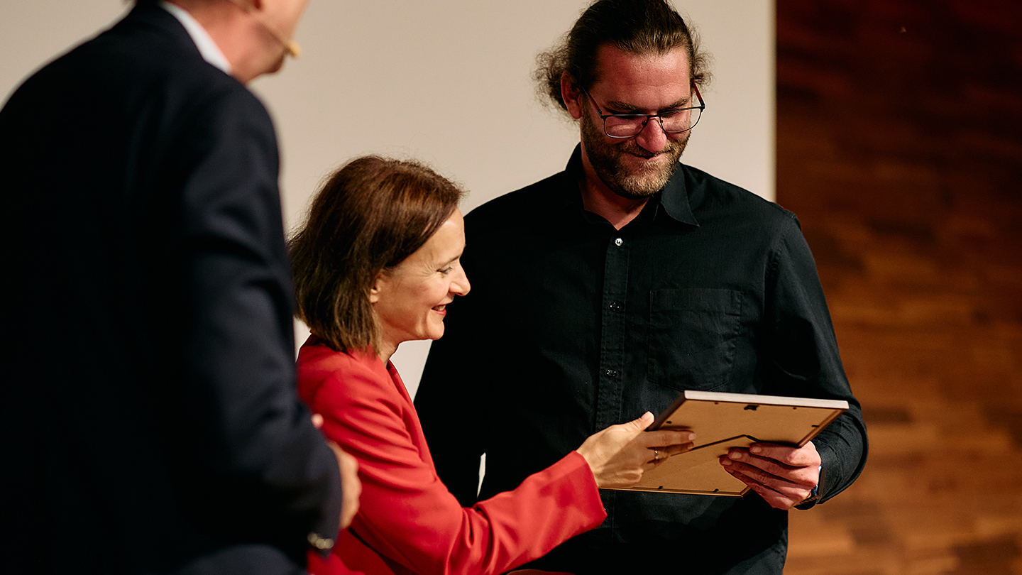 Daniel Mitsche nimmt ihren Annerkennungspreis von Mirela Toljan Jakomin entgegen
