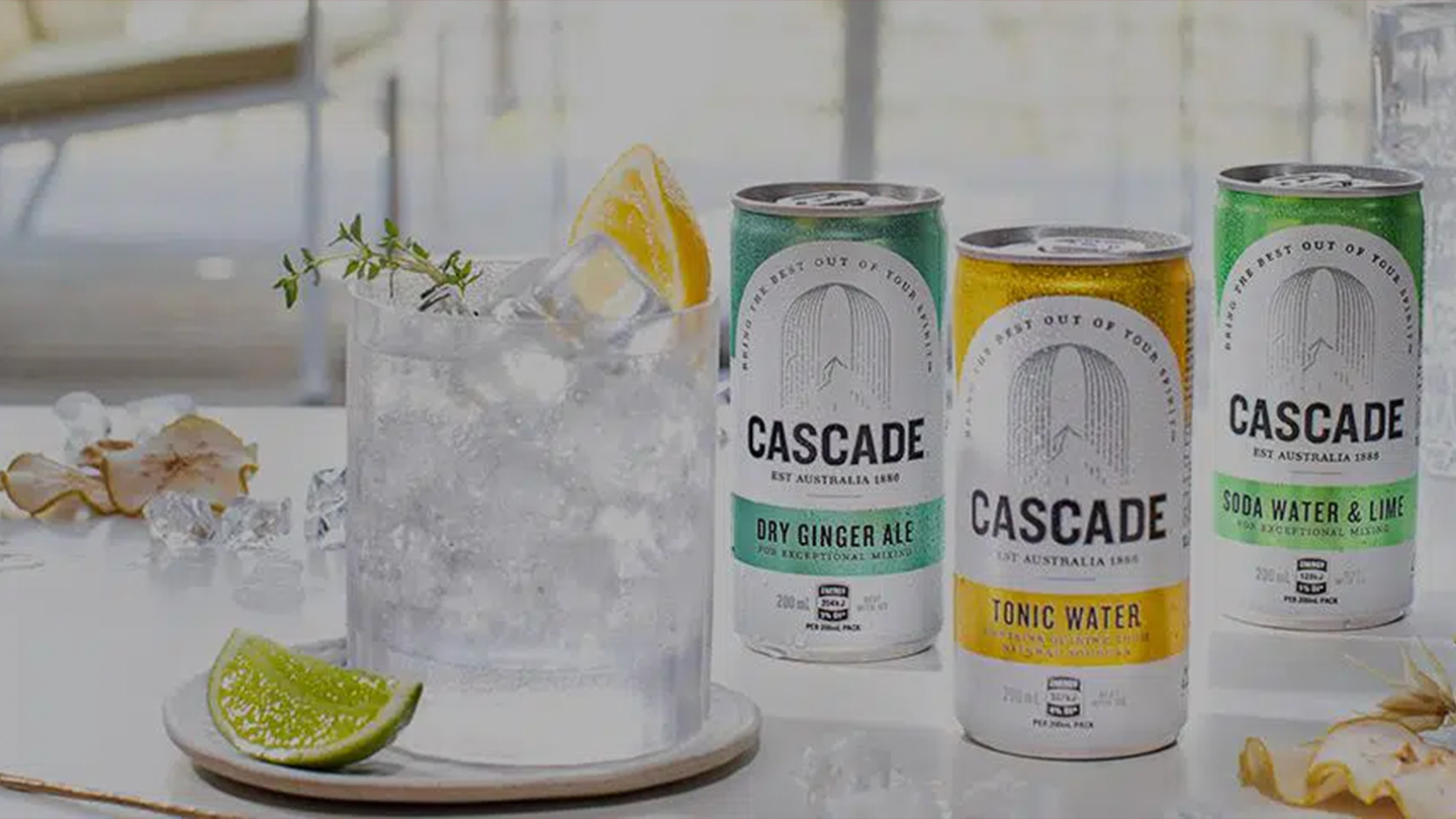  Three Cascade cans on top of a table with glass full of ice and orange slices