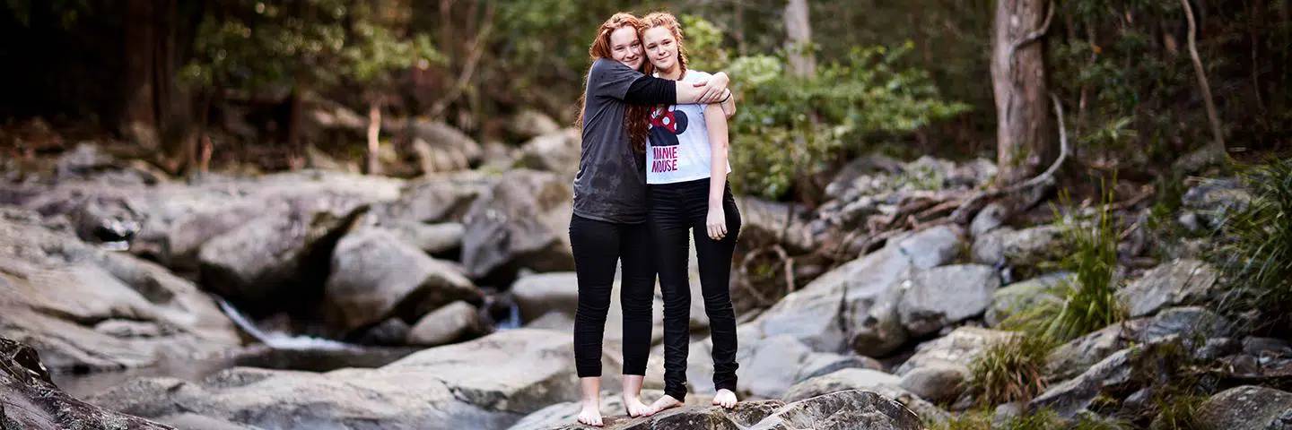 Two women hugging in a forest