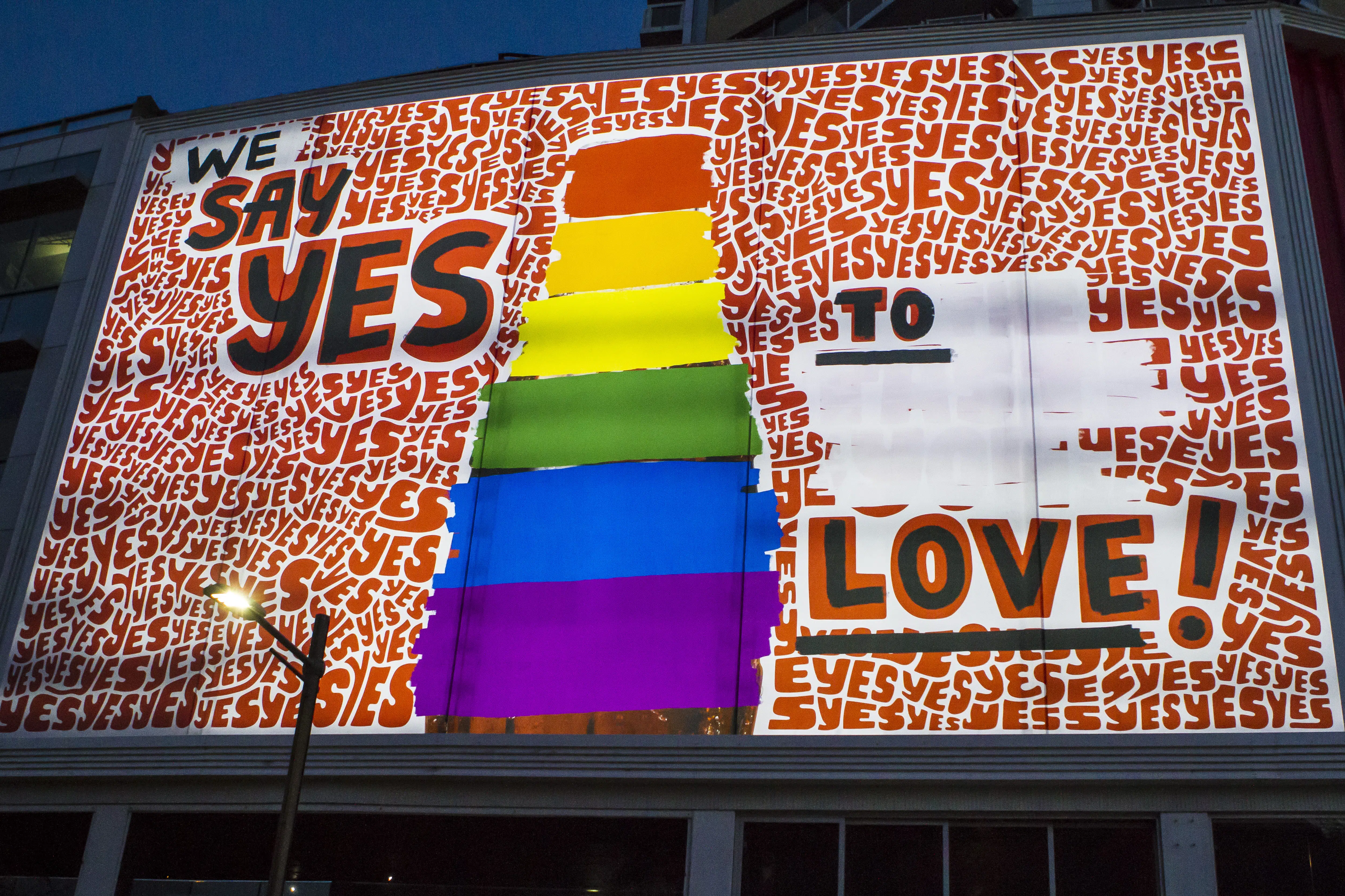 Banner with illustration of a Coca-Cola bottle with multiple colors and the phrase 'We say yes to love!'