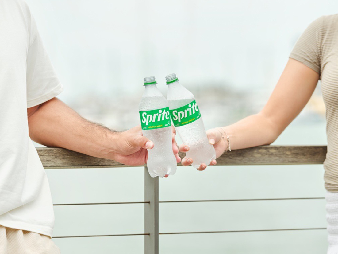 Detail of a hand putting an empty Coca-Cola plastic bottle in a recyclable trash bin