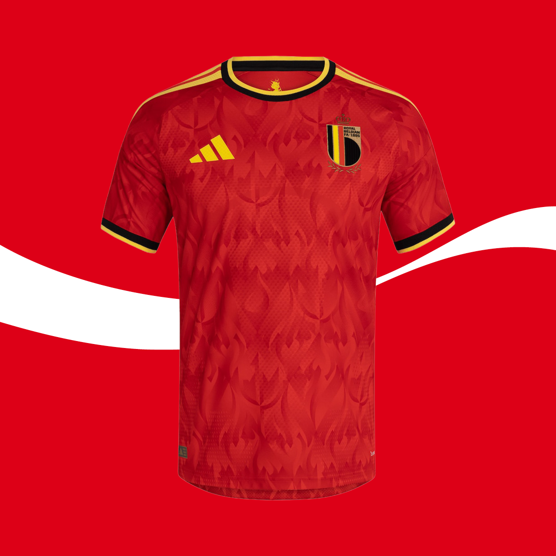 Maillot de football belge rouge avec un motif discret de flammes, des détails jaunes et noirs, l’écusson national sur la poitrine et un logo de marque, présenté sur un fond rouge.
