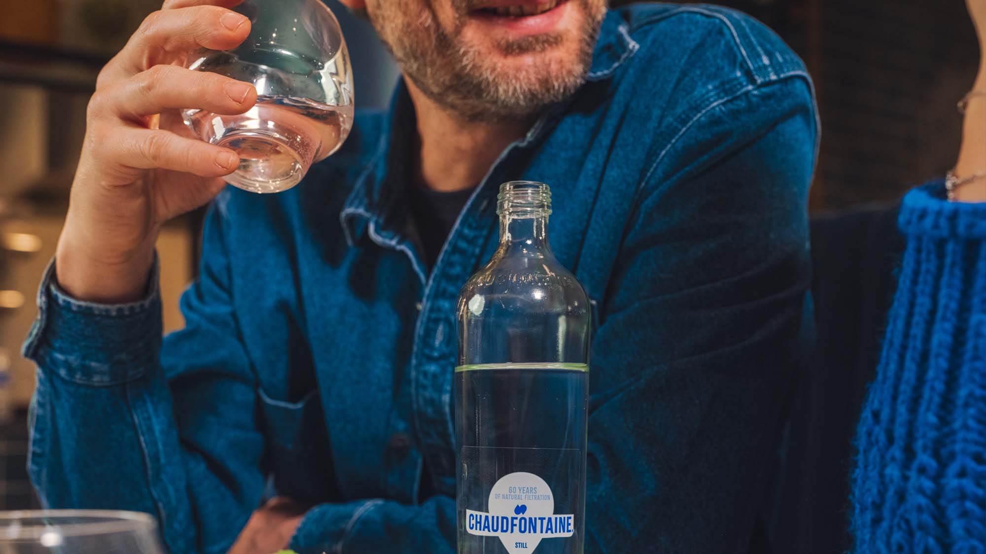 Een man die Chaudfontaine mineraalwater uit een glas drinkt