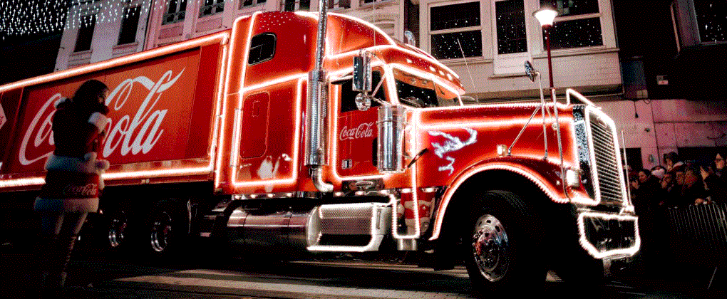 Coca-Cola kersttruck met verlichte lampjes en logo, verspreidt feestelijke sfeer