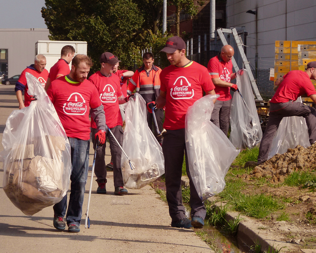 Vrijwilligers dragen een Coca-Cola T-shirt en verzamelen afval om een duurzame wereld te creëren