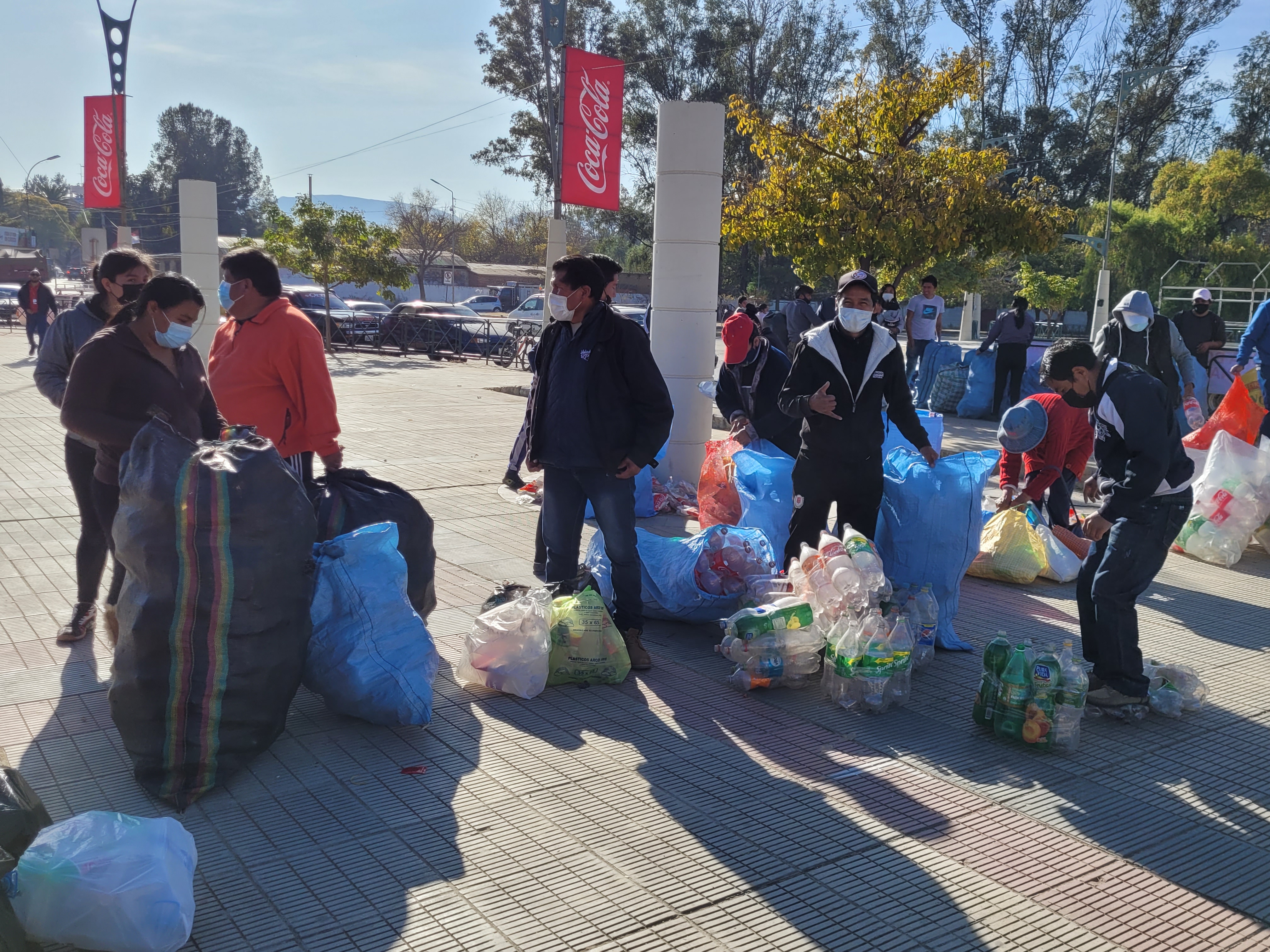Varias personas con bolsas llenas de botellas de plástico vacías