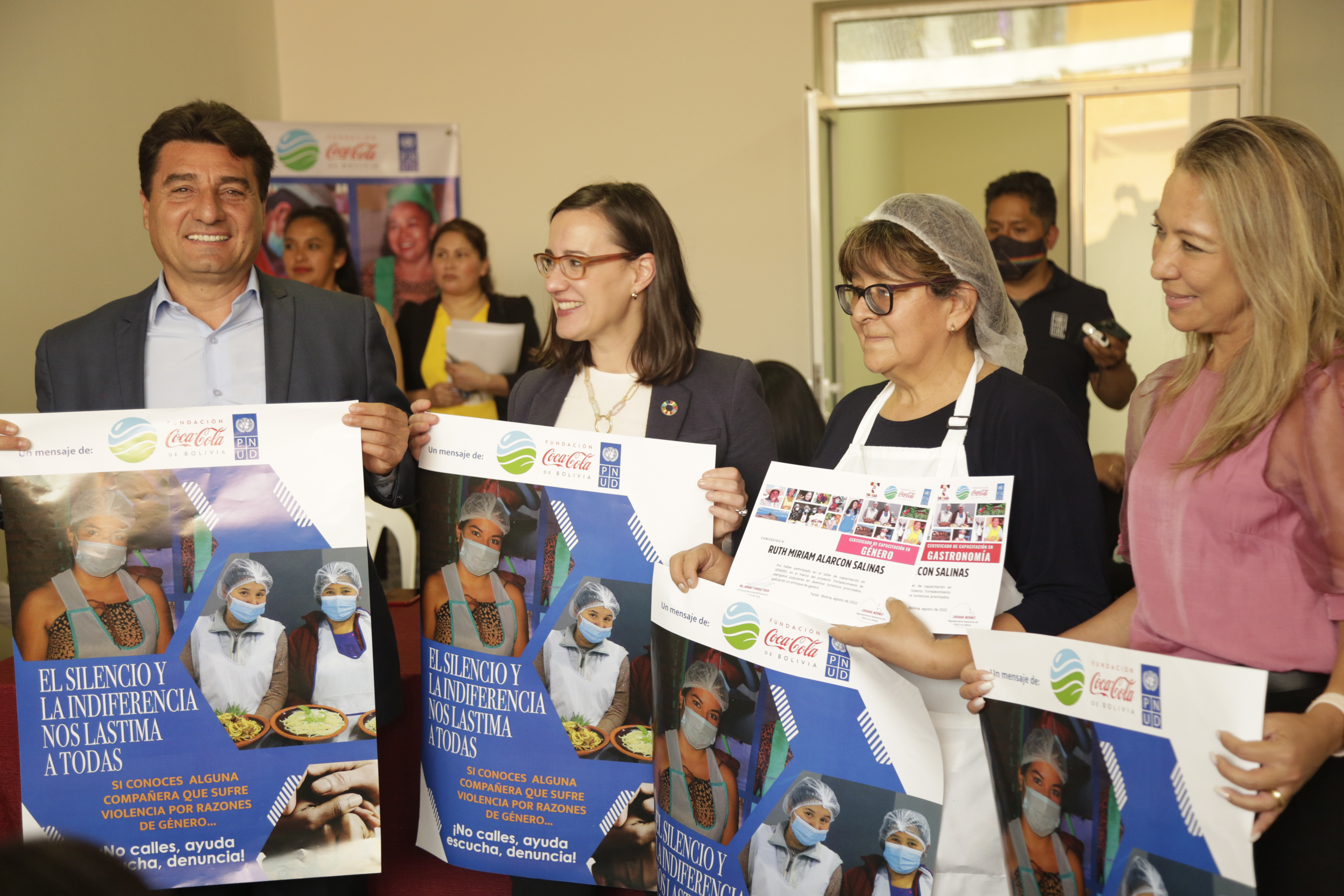Cuatro personas sonríen y posan con carteles