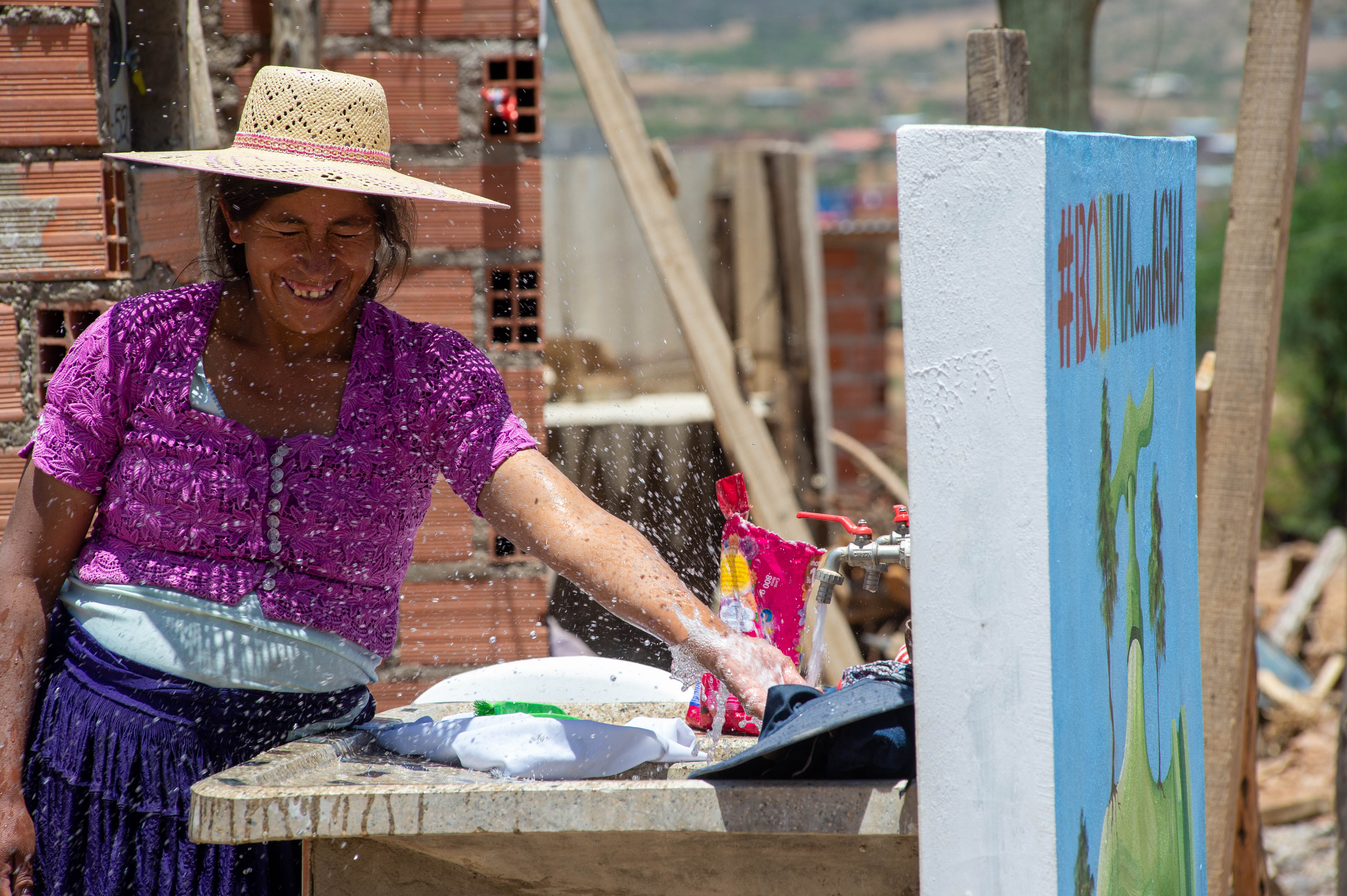 Una mujer se ríe mientras el agua de una fuente le salpica