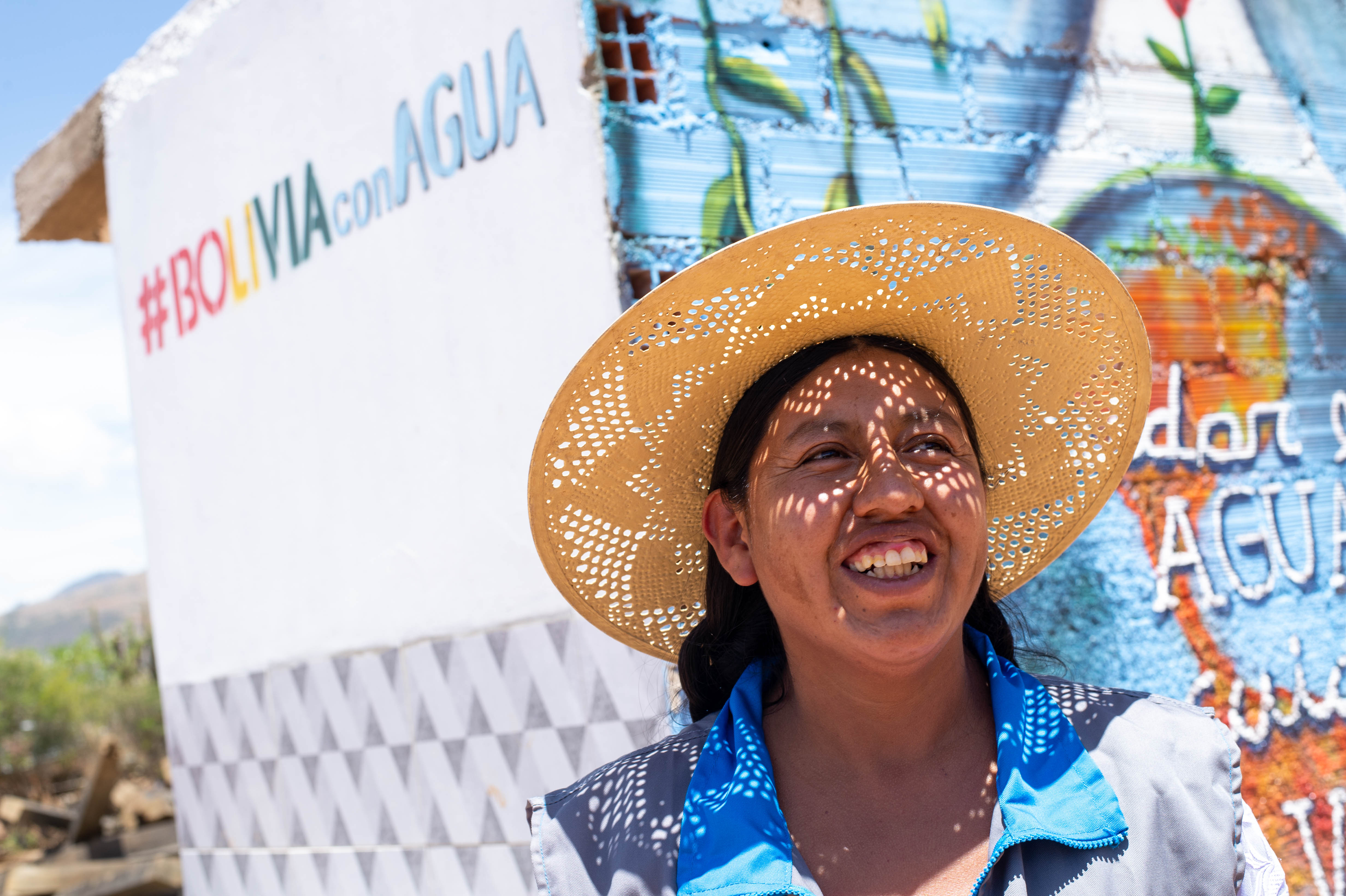 Mujer sonriente con sombrero sobre fondo pintado