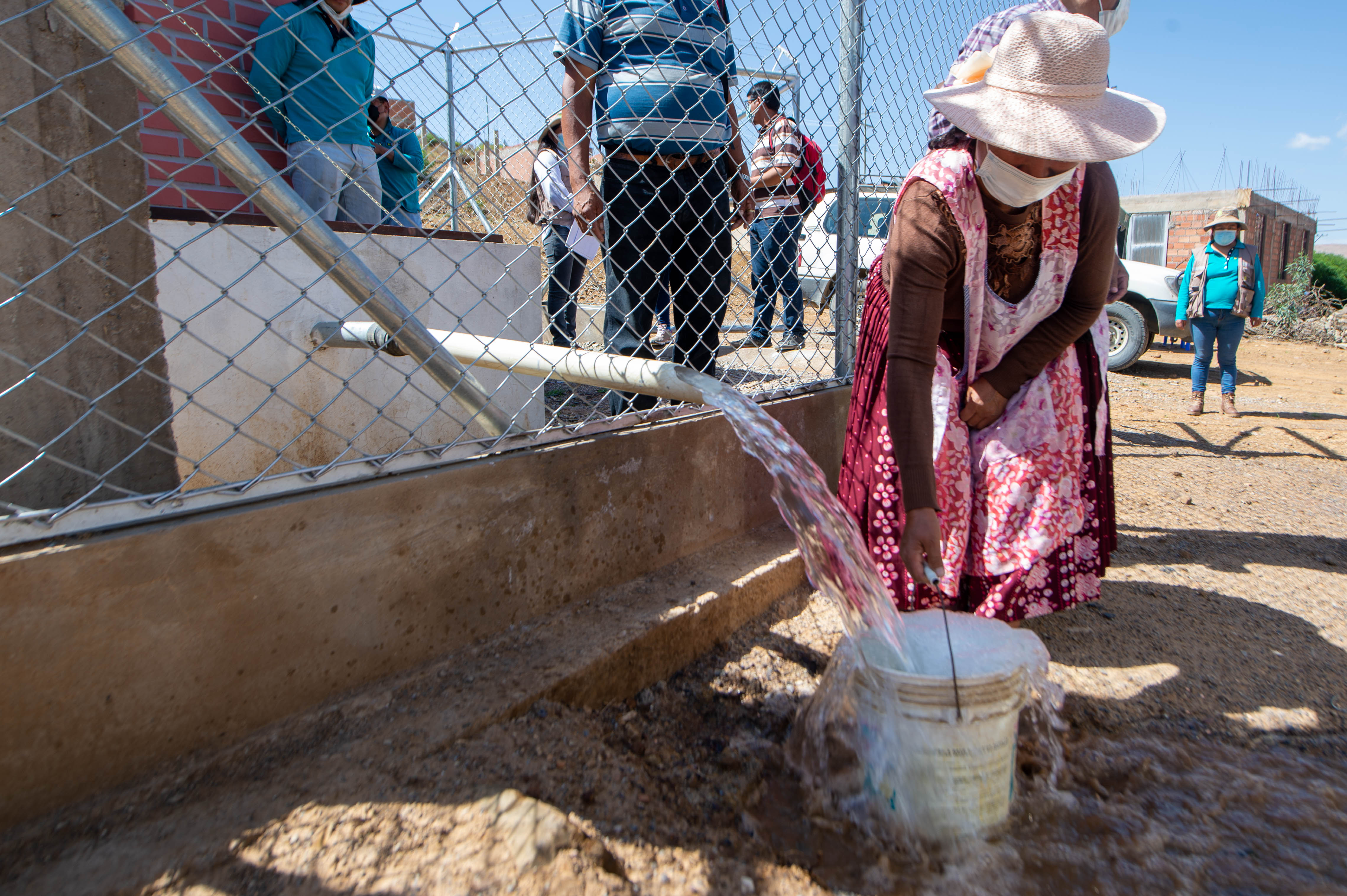 Una mujer llena un cubo de agua en una fuente