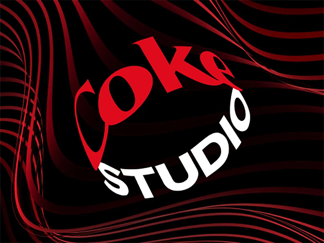 El artista Camilo tomándose de su bigote delante de un fondo negro con líneas rojas y el logo de Coke Studio junto a un texto que dice “Experimenta la magia de la música”
