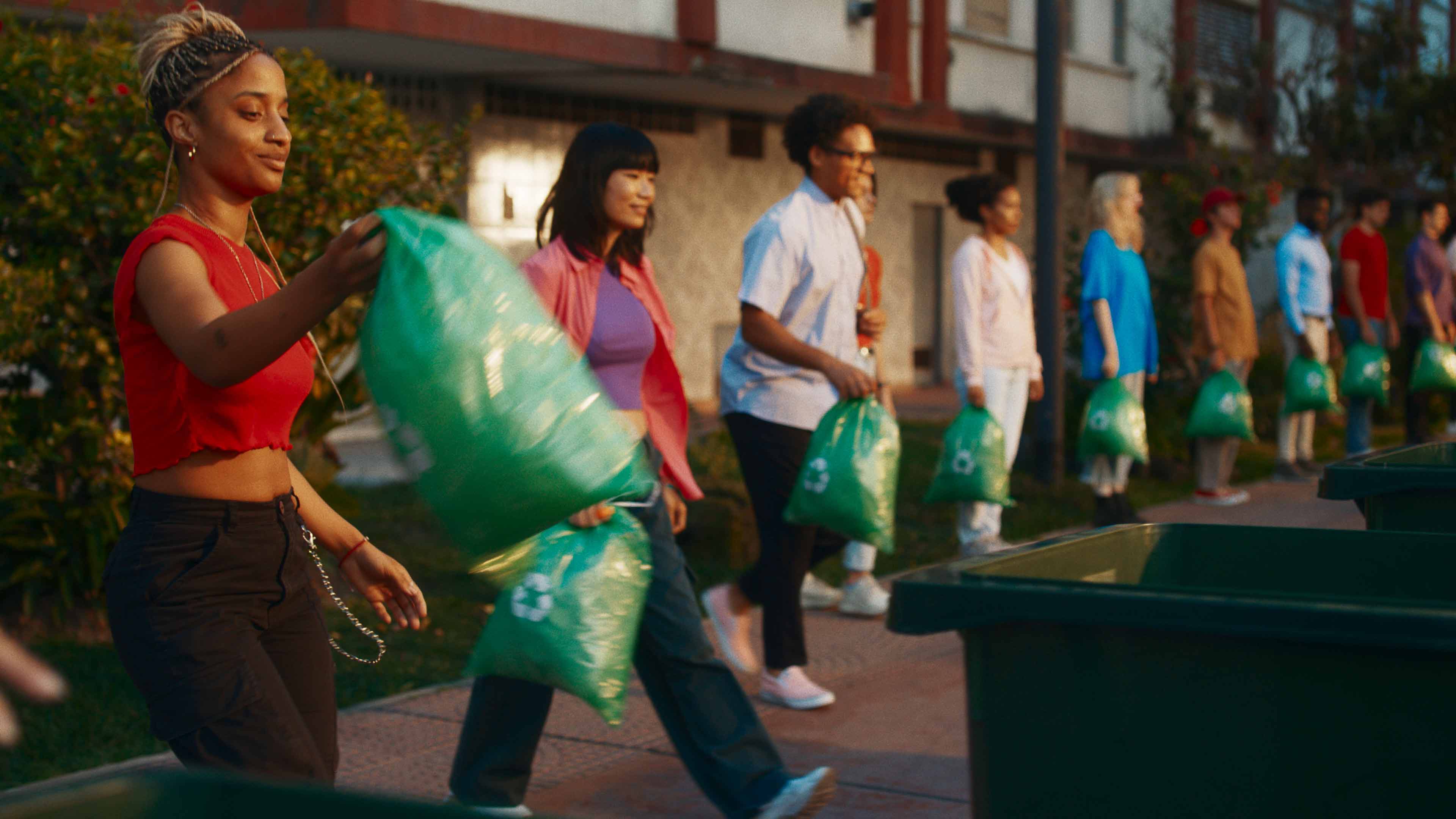 Personas sacan la basura reciclable en bolsas verdes