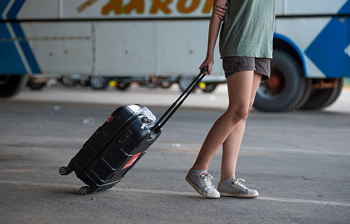 Una mujer lleva una valija pequeña en una terminal de ómnibus