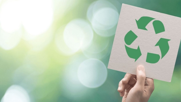 Mano sostiene un cartel con el logo de reciclaje