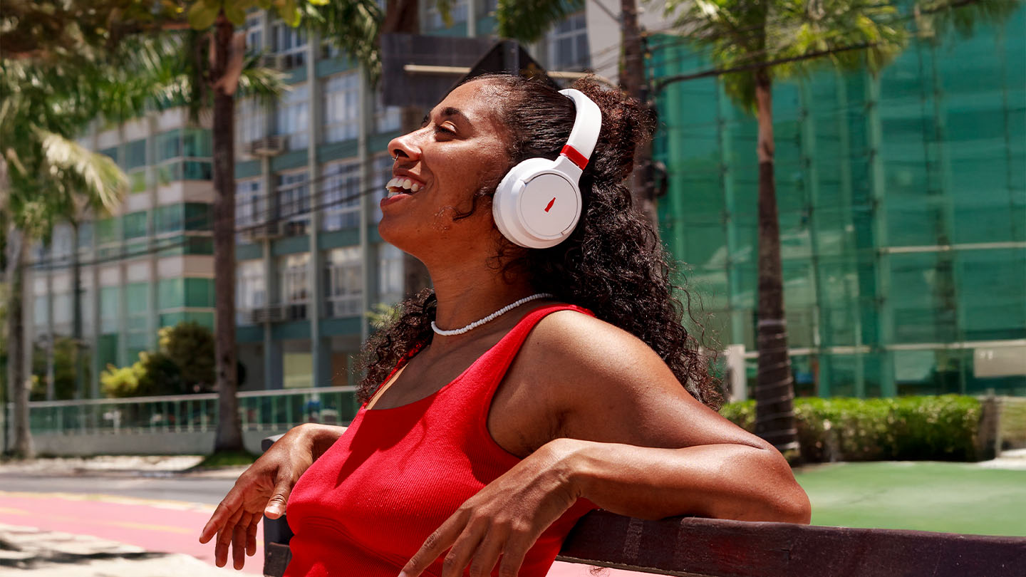 Uma mulher sentada em um banco, ouvindo música com seus fones de ouvido sem fio.