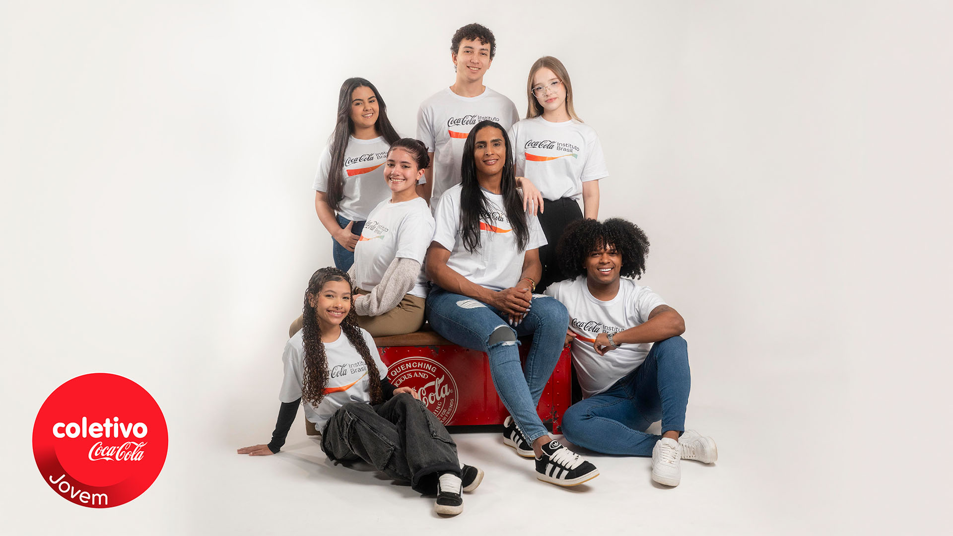 Grupo de jovens posando ao lado do logotipo do coletivo Jovem.