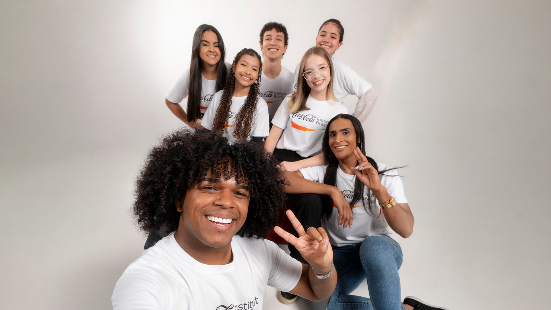Grupo de jovens posando juntos sorrindo alegremente.
