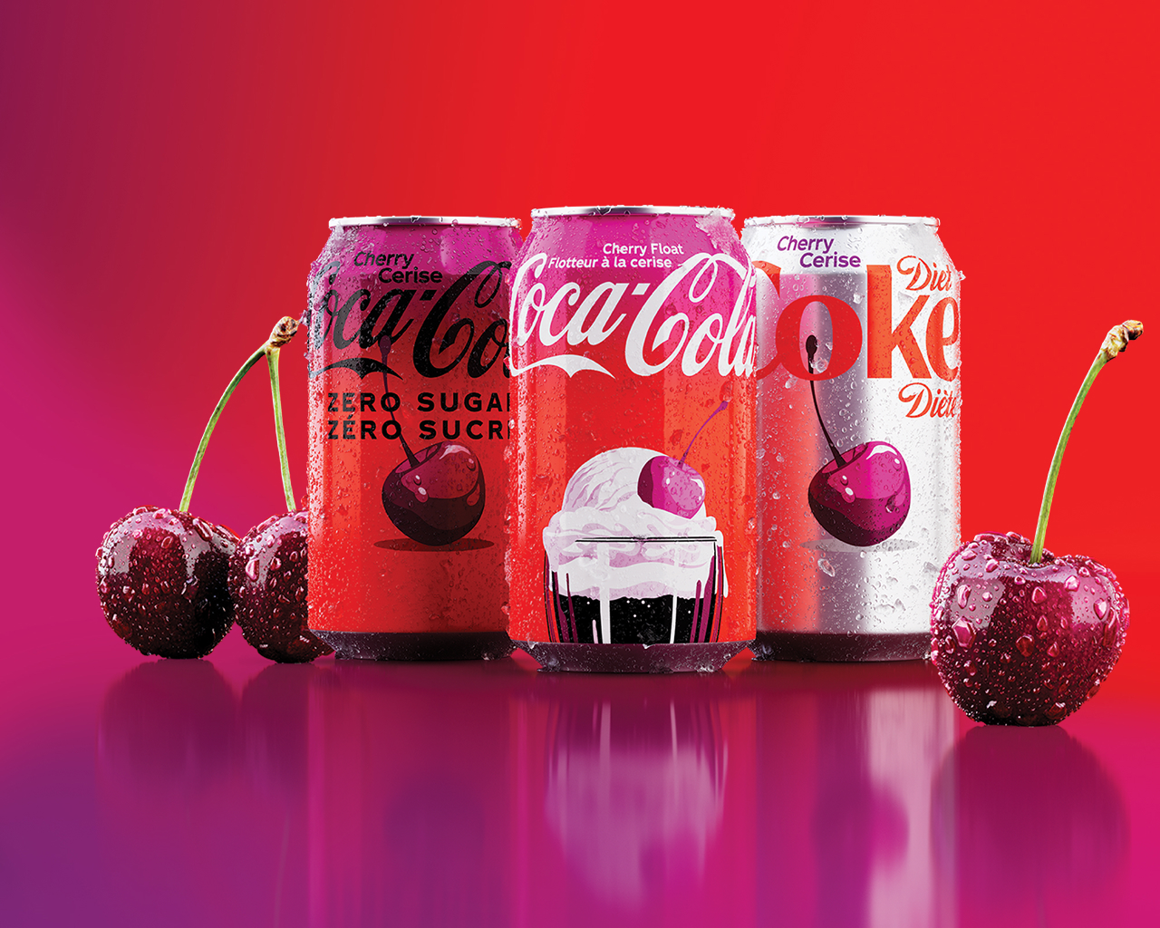 Three Cherry-flavoured Coca-Cola cans—Zero Sugar (Zéro sucre), Cherry Float, and Diet Coke Cherry (Diète)—stand side by side against a red background with fresh cherries and their reflections visible below.