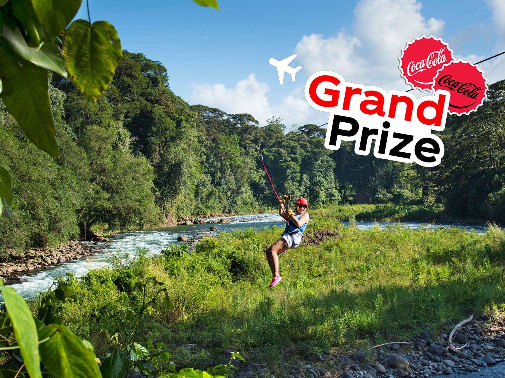 A hiker in a tropical rainforest stands on a cliff looking at the ocean. A colorful sticker with an airplane says, “Grand Prize.”