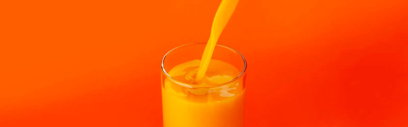 A glass of orange juice being poured