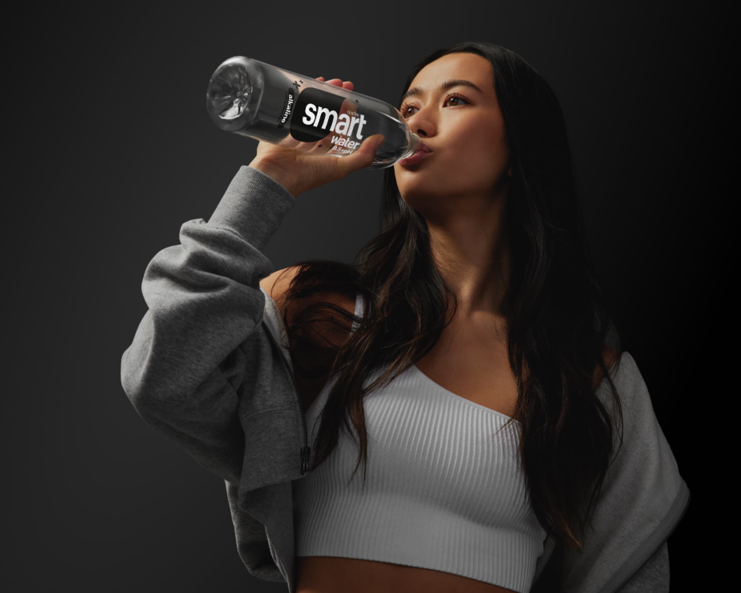 a woman drinking a bottle of smartwater