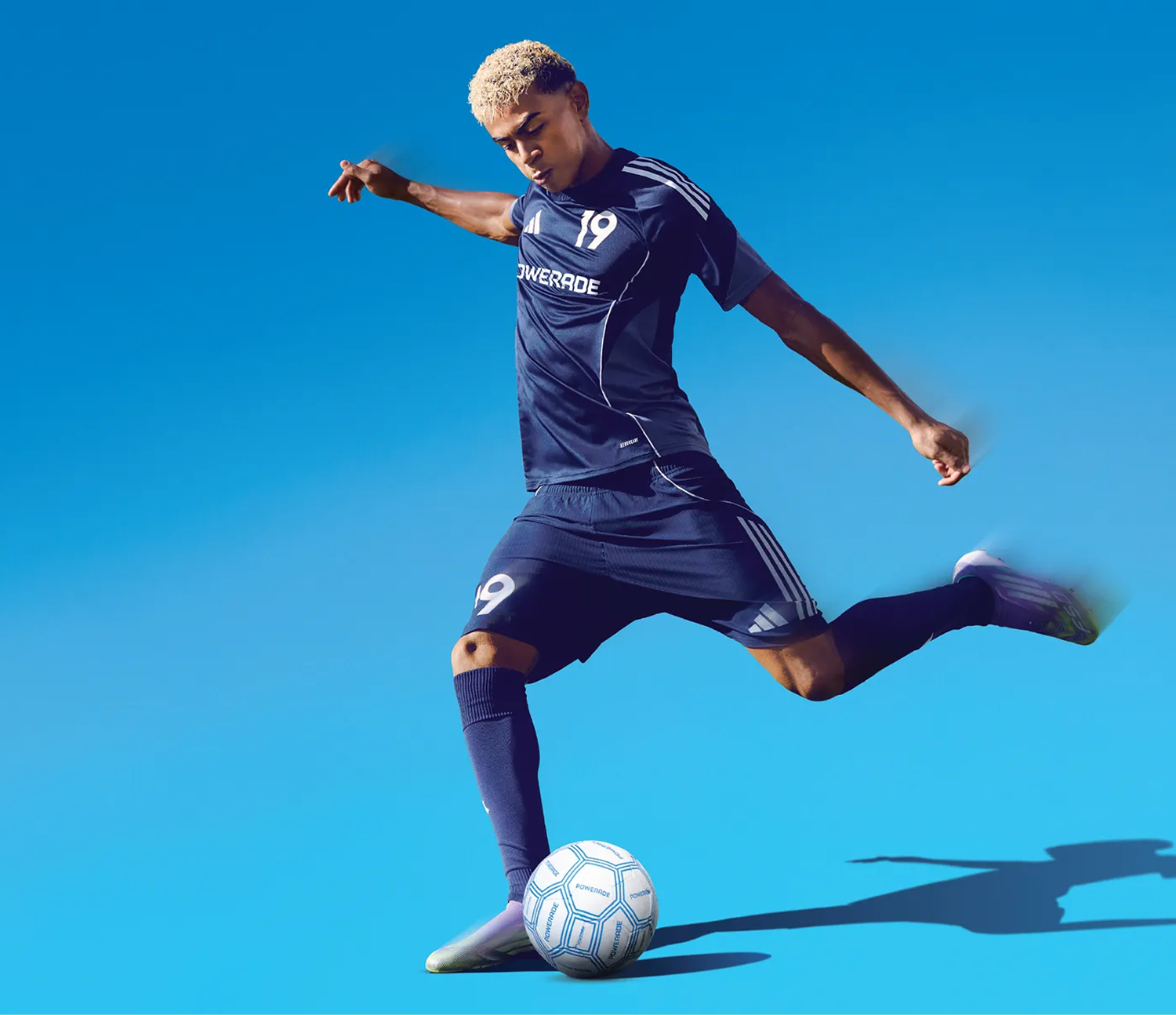 A soccer player kicking a ball on a blue background
