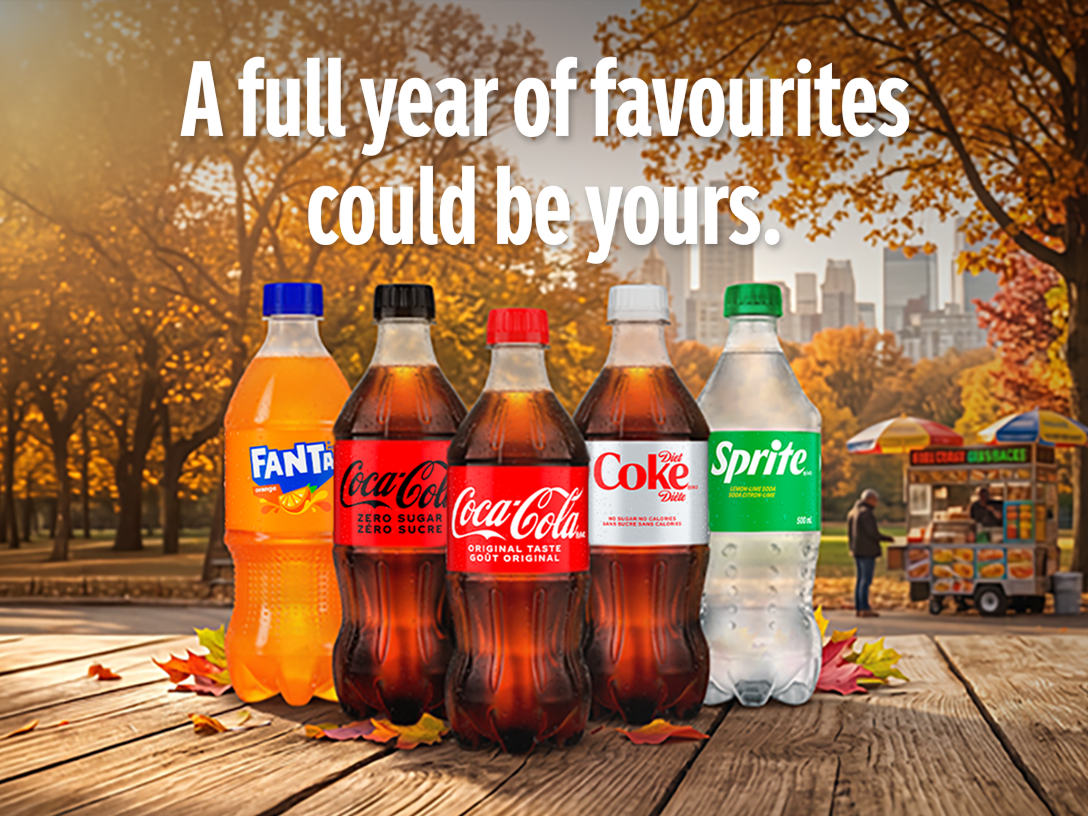 Assorted Coca-Cola beverages on an autumn park table promoting a chance to win a full year of favourites.