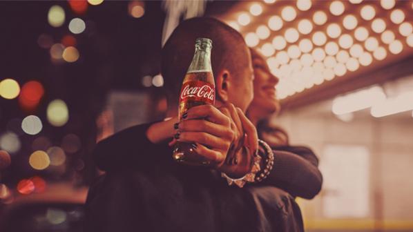 Two people hugging while one of them is holding a Coca-Cola bottle