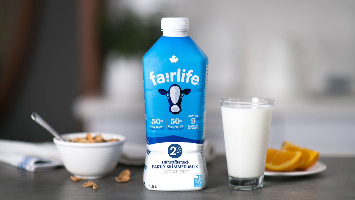 A fairlife® milk packaging, a glass of milk and a cereal bowl side by side