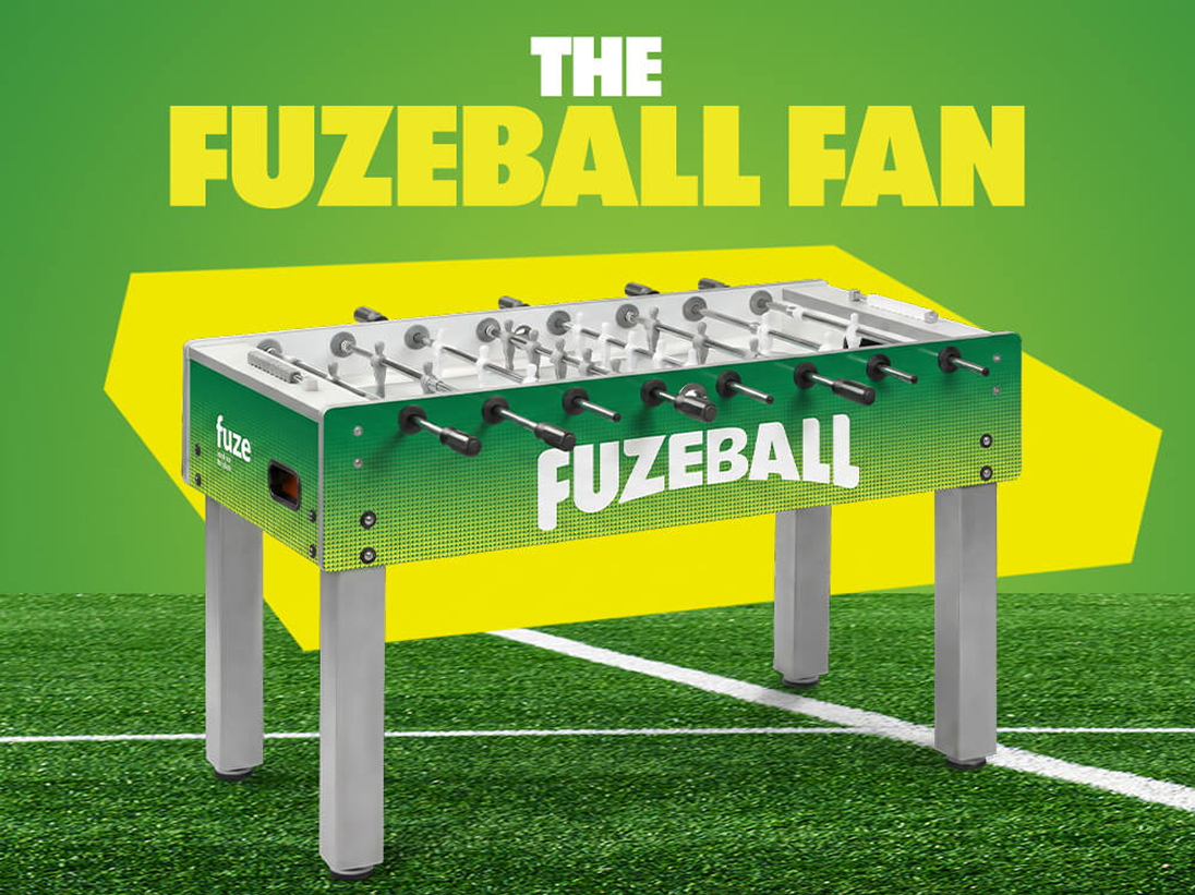 Fuzeballer Week 6 hero showing green Fuzeball table on soccer field with bold title THE FUZEBALL FAN on bright yellow backdrop.