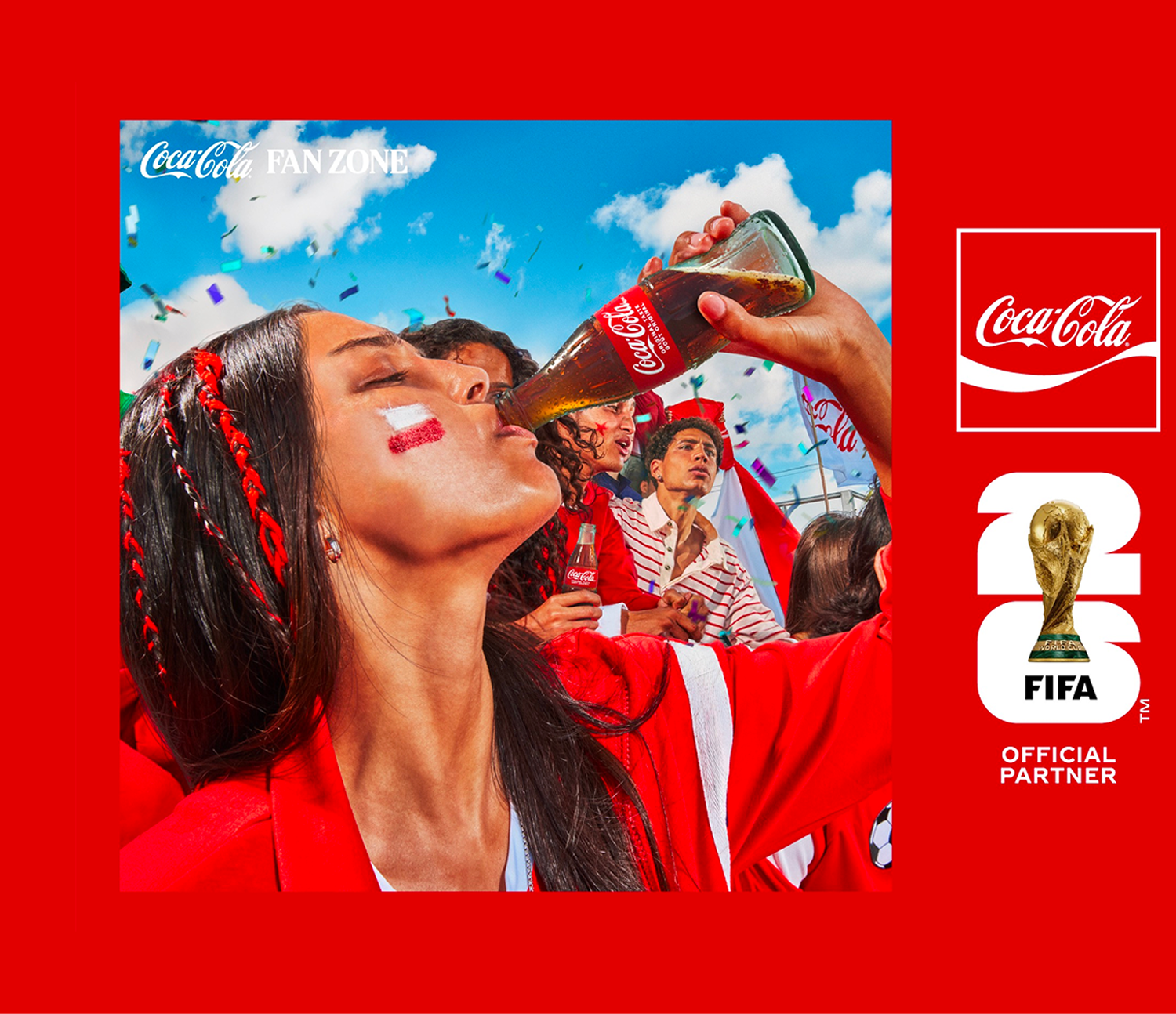Fans in red celebrating at Coca-Cola FIFA Fan Zone, woman raising a Coke bottle amid confetti and FIFA World Cup branding.