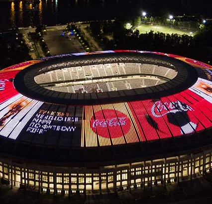 Vue de dessus d'un stade de football la nuit avec de la publicité Coca-Cola dessus