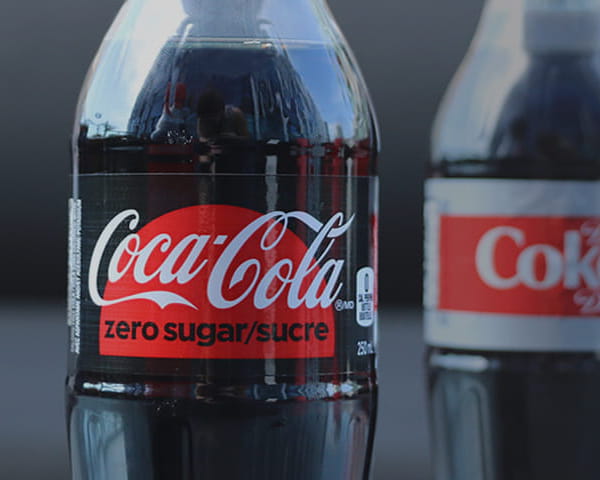 Un gros plan de bouteilles en plastique contenant du Coke Diète et du Coca-Cola zéro sucre